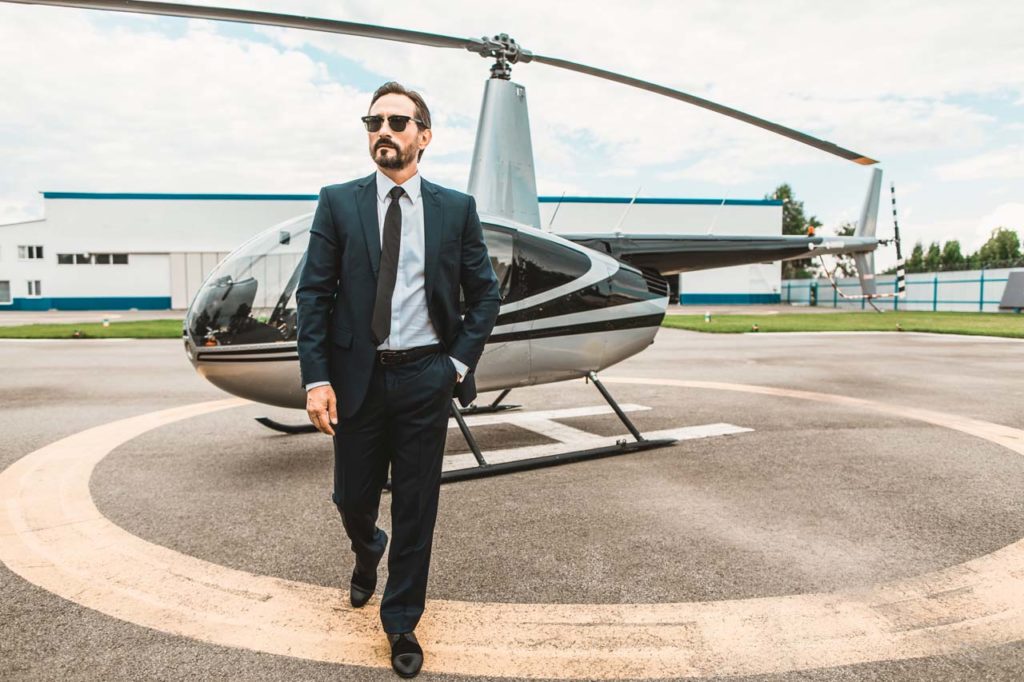 Confident businessman wearing glasses and walking from the helicopter